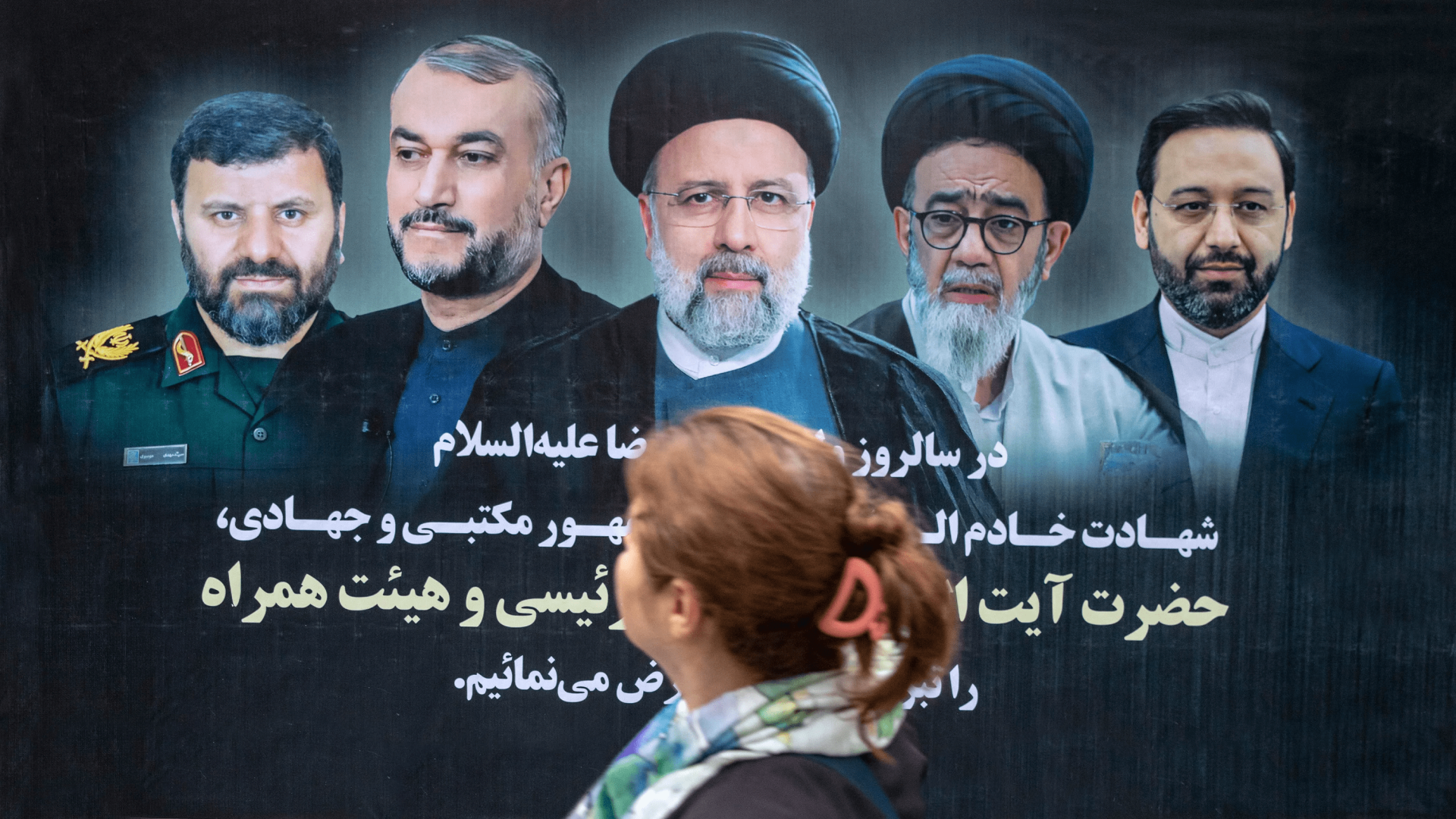 A woman passes by a poster of Iran's late president Ebrahim Raisi who died in a helicopter crash.