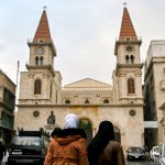 Muslim women walk near a church in Syria