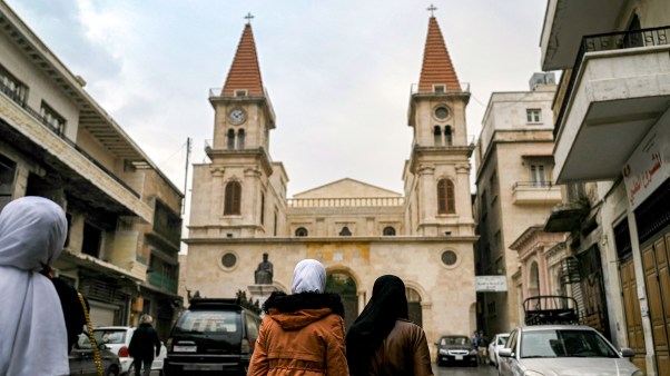 Muslim women walk near a church in Syria