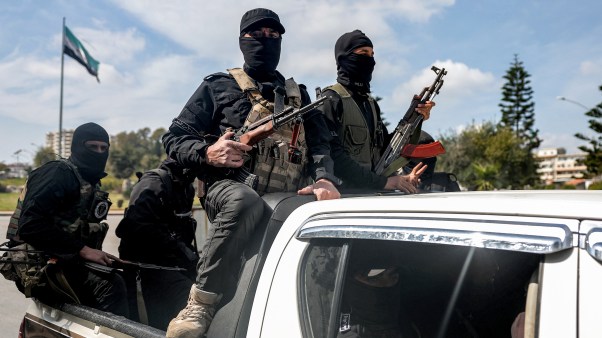 Security forces loyal to the interim Syrian government ride in the back of a vehicle.