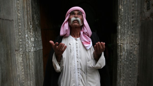 A Yazidi man prays at the entrance of a temple in Iraq.