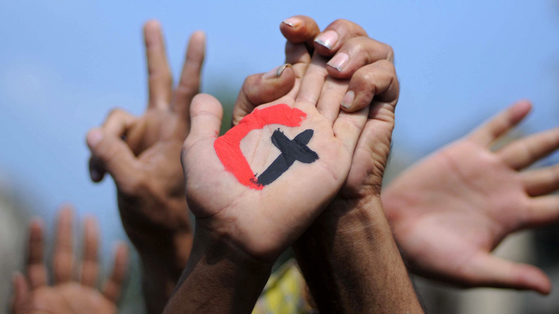 A cross representing Christianity and a crescent representing Islam painted on the palm of a demonstrator during a rally in support of national unity in Egypt.